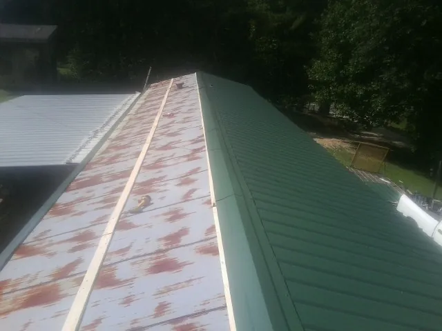 Old rusted panels beside newly installed green metal roofing — Wind Damage Roof Repair by Roofing Brothers in Castle Dale