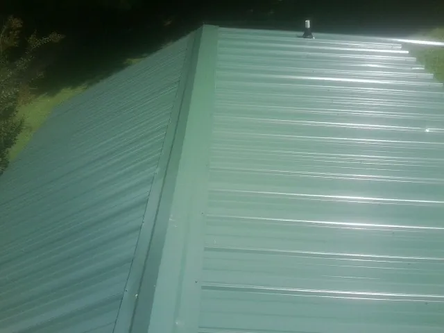 New green metal panels meeting at the ridge of a roof — Flat Roof Repair work by our crew in Castle Dale