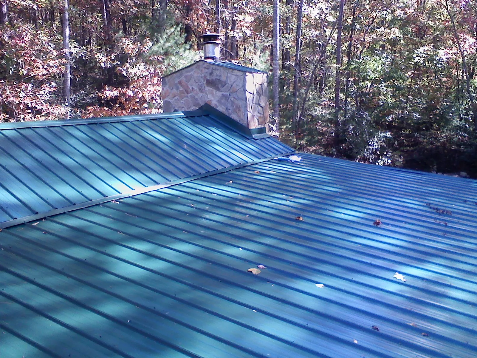 New green metal roof and stone chimney surrounded by autumn woods in Castle Dale