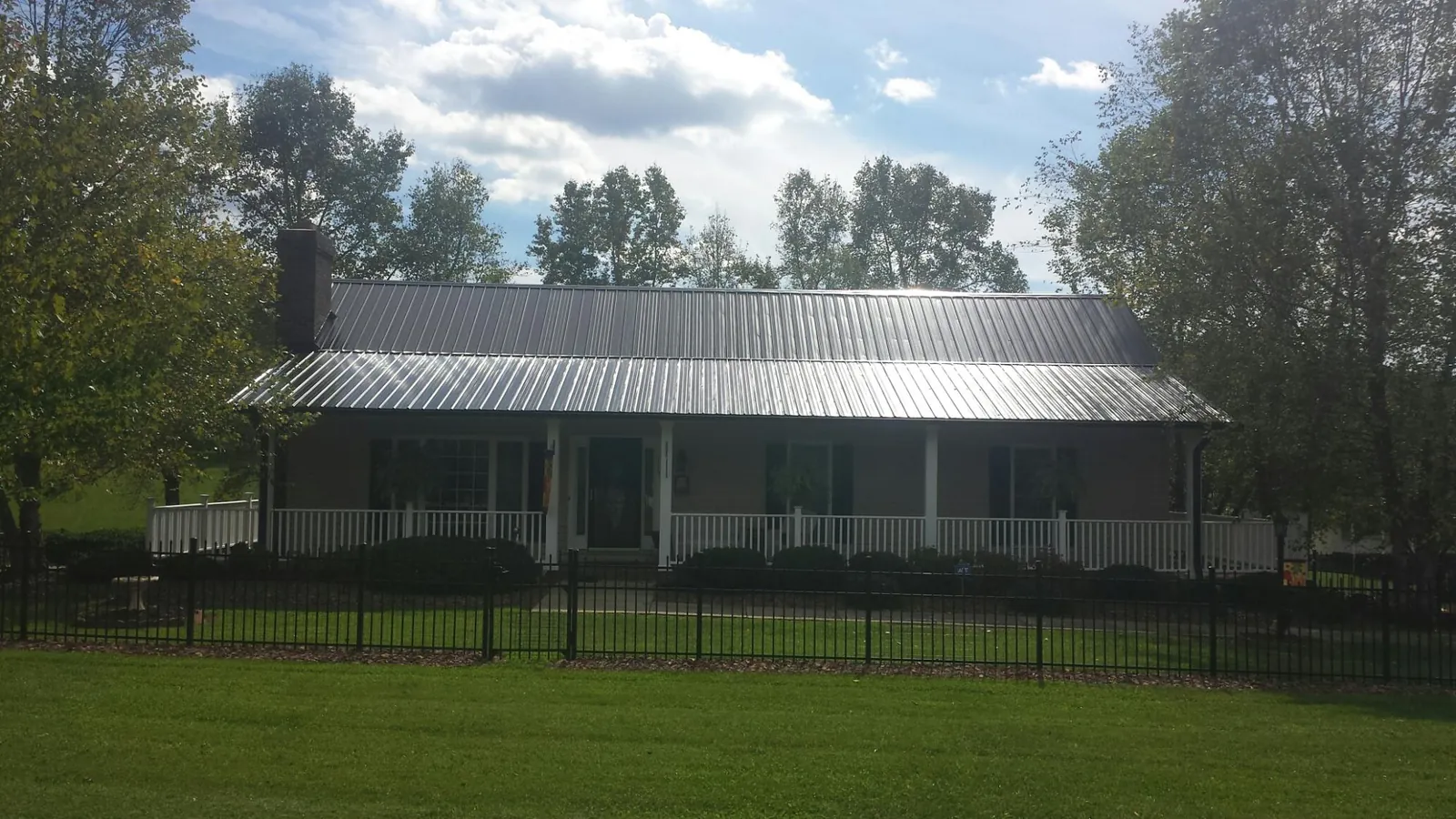 Gray metal roof on a brick ranch with a full width front porch — Gutter Guard Installation work by our crew in Castle Dale