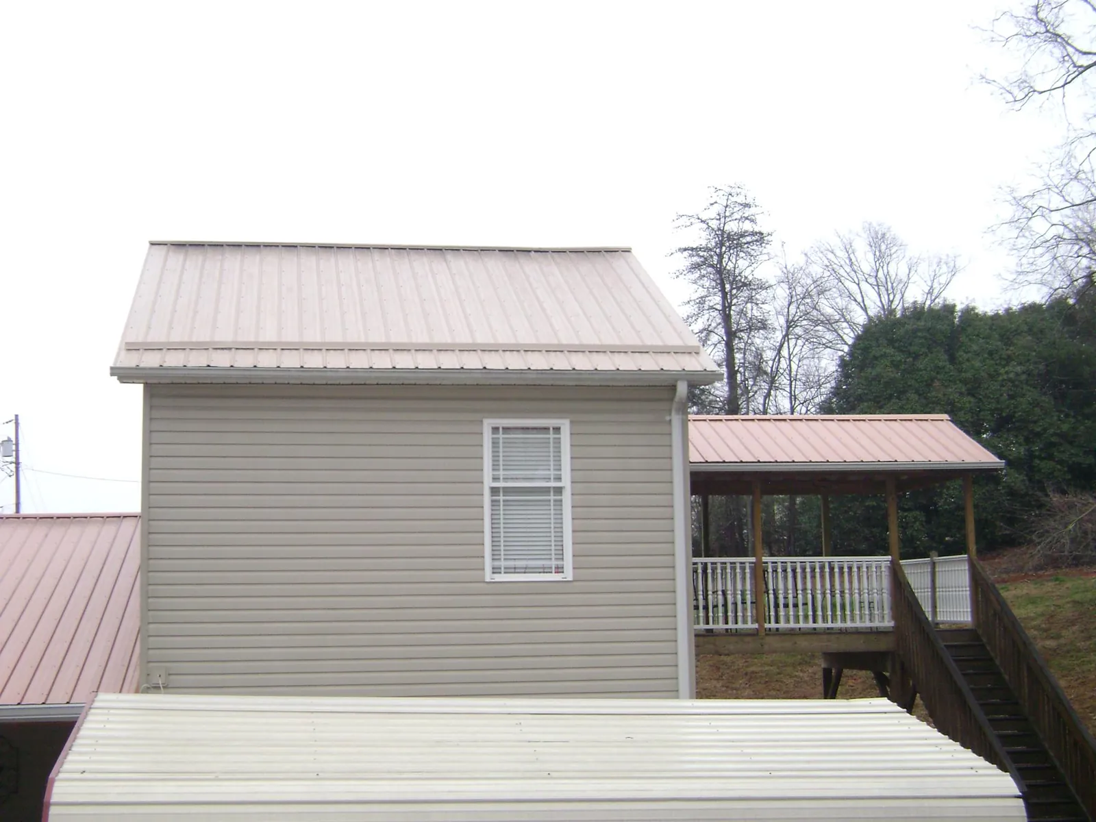 Tan metal roofs on a two story addition and attached porch, from a Roof Replacement job in Castle Dale