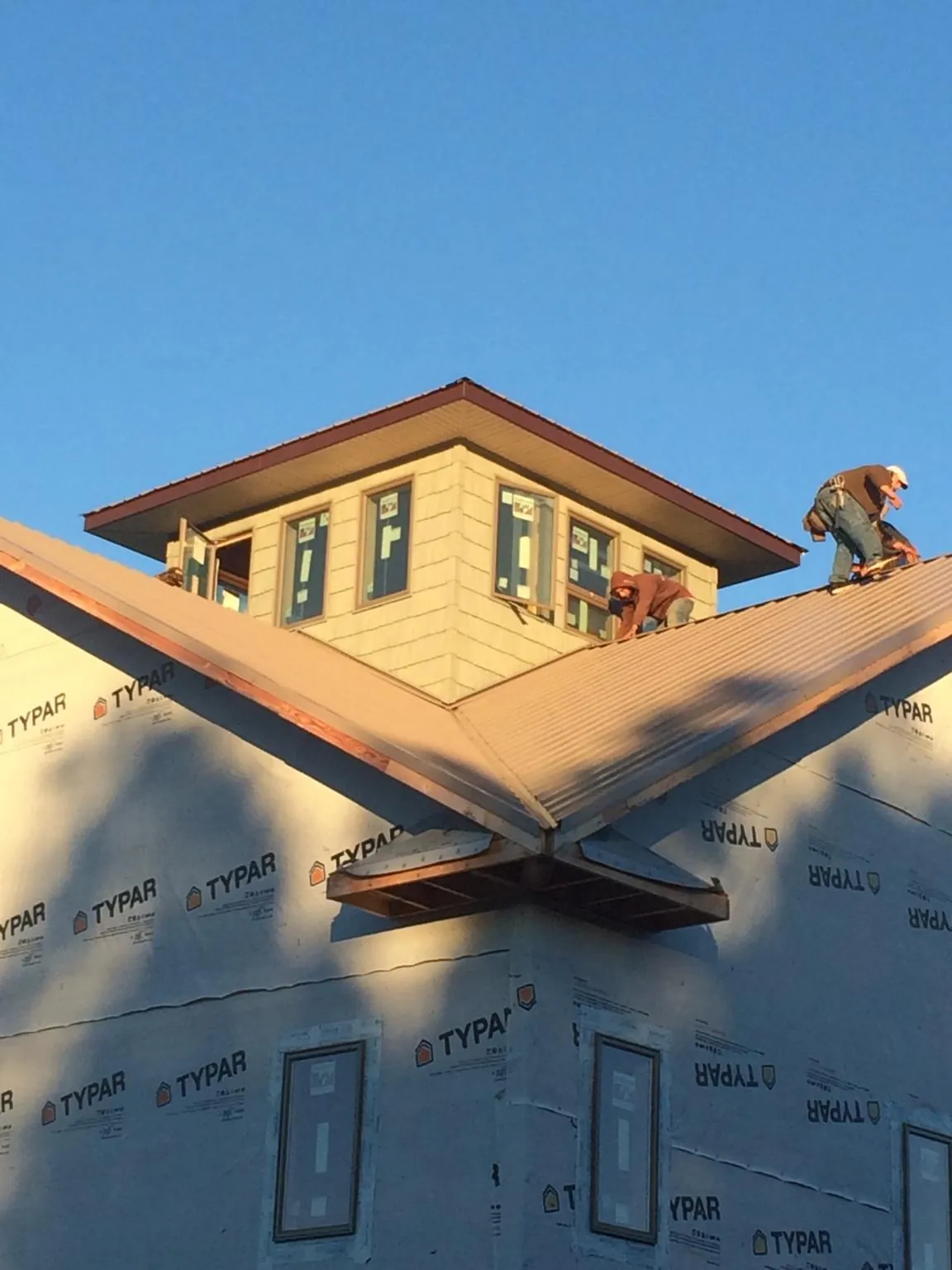Roofers working around a rooftop cupola on a new metal roof at sunset — Roof Waterproofing in Castle Dale by Roofing Brothers